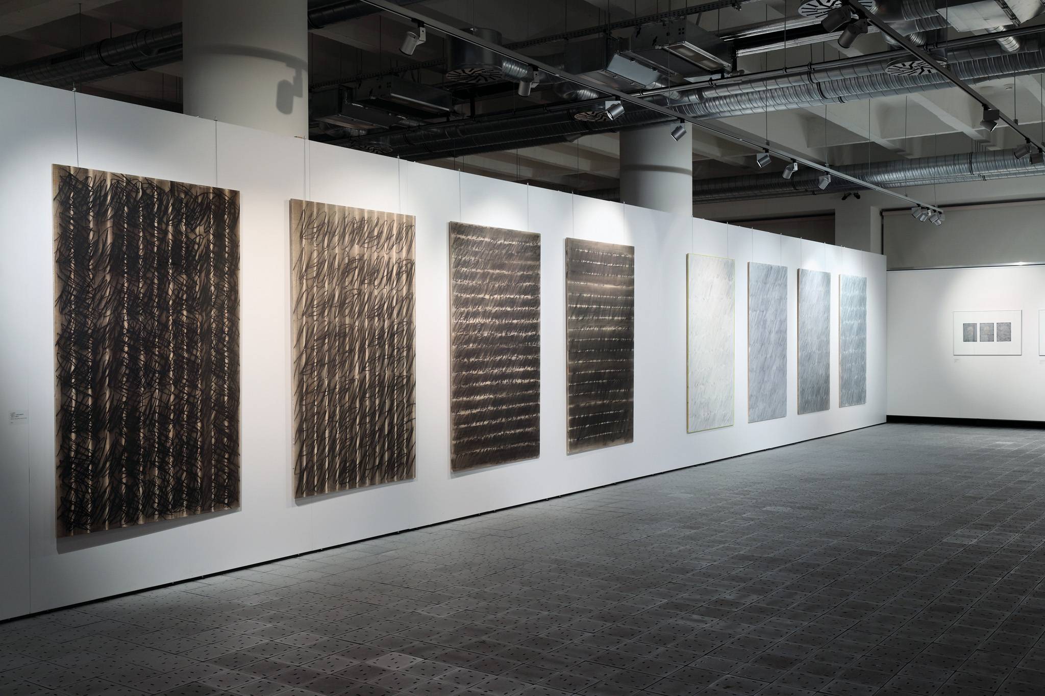 Pohled do expozice výstavy Makulatury atd., 8 x / Město v zahradách „Noc a den“, laťovka, olej, grafit, mastný pastel, 125 x 200 cm, 2014. Fotografická dokumentace projektu Dalibor Novotný. Fotoarchiv Krajské galerie výtvarného umění ve Zlíně.